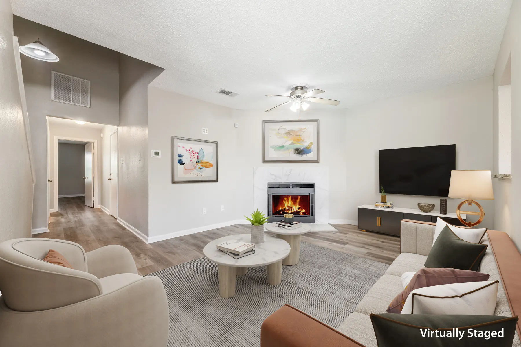 Open living area with fireplace and wood-style floors (virtually staged)